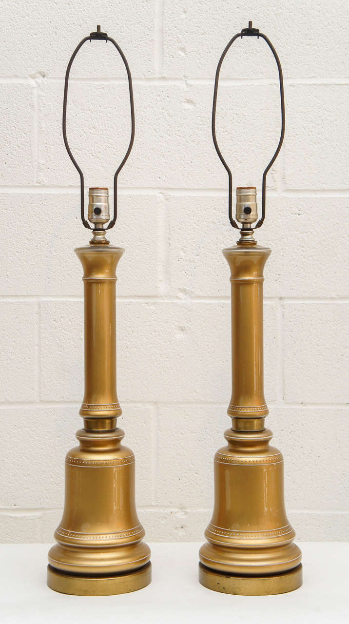 Here is a beautiful pair of gold Opaline lamps. The lamps are painted on the underside with white detail trim on the outside. The harps are fixed.