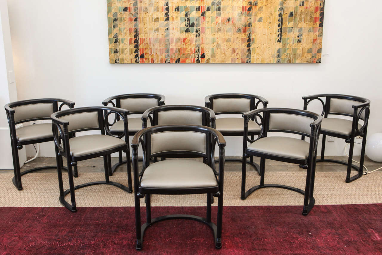 These striking barrel-back dining chairs, designed by Josef Hoffman in 1906 for the Wiener Werkstatte, feature a black lacquered frame with a seat and back newly upholstered in a pebbled silver. The curvaceous design of the chairs is echoed in the