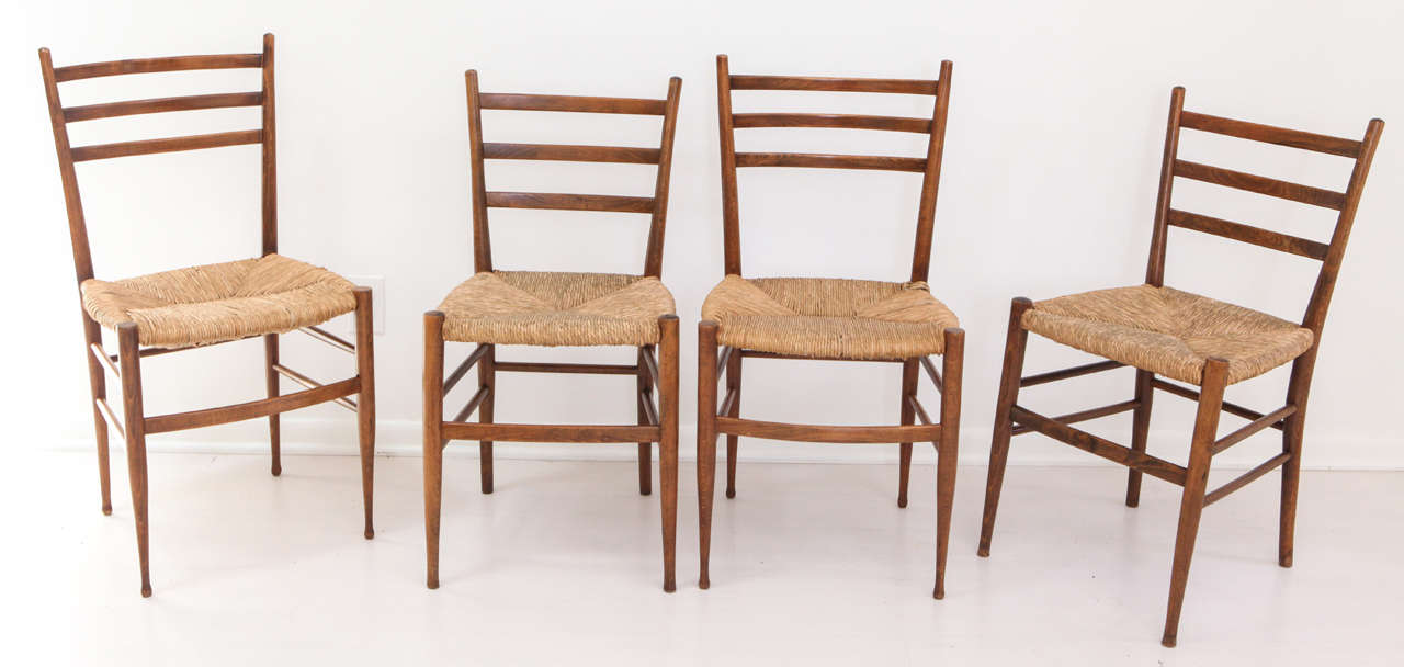 A classic set of dining chairs with ladderback and rush seats, circa 1960s. Lightweight and perfect for daily use at the dining table, this collection of four oak and rattan chairs is in fantastic vintage condition and make for great supplementary