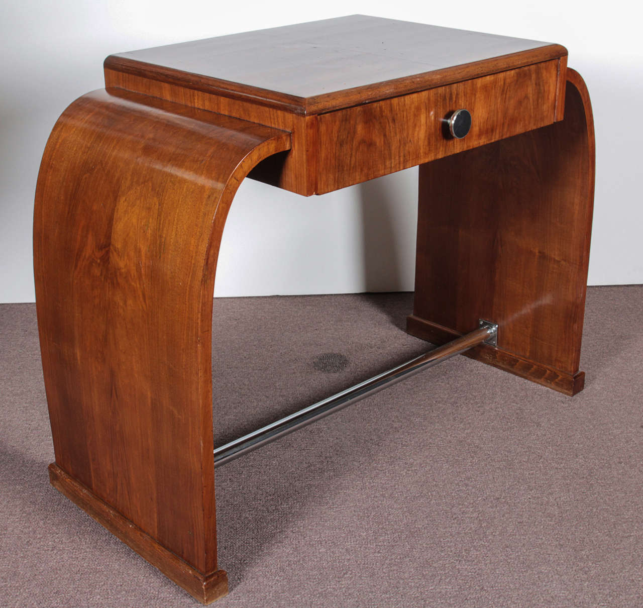 A lovely, original French Art Deco walnut desk/ vanity. Typical Art Deco waterfall design in book matched walnut, single drawer, tubular chrome foot rest and chrome hardware pull.
Although the maximum depth at the top is 19
