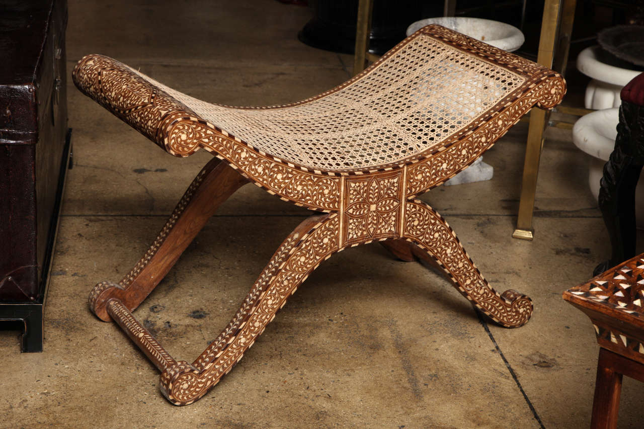 A footstool with bone inlays in classic pattern throughout, from India. With cane seat.