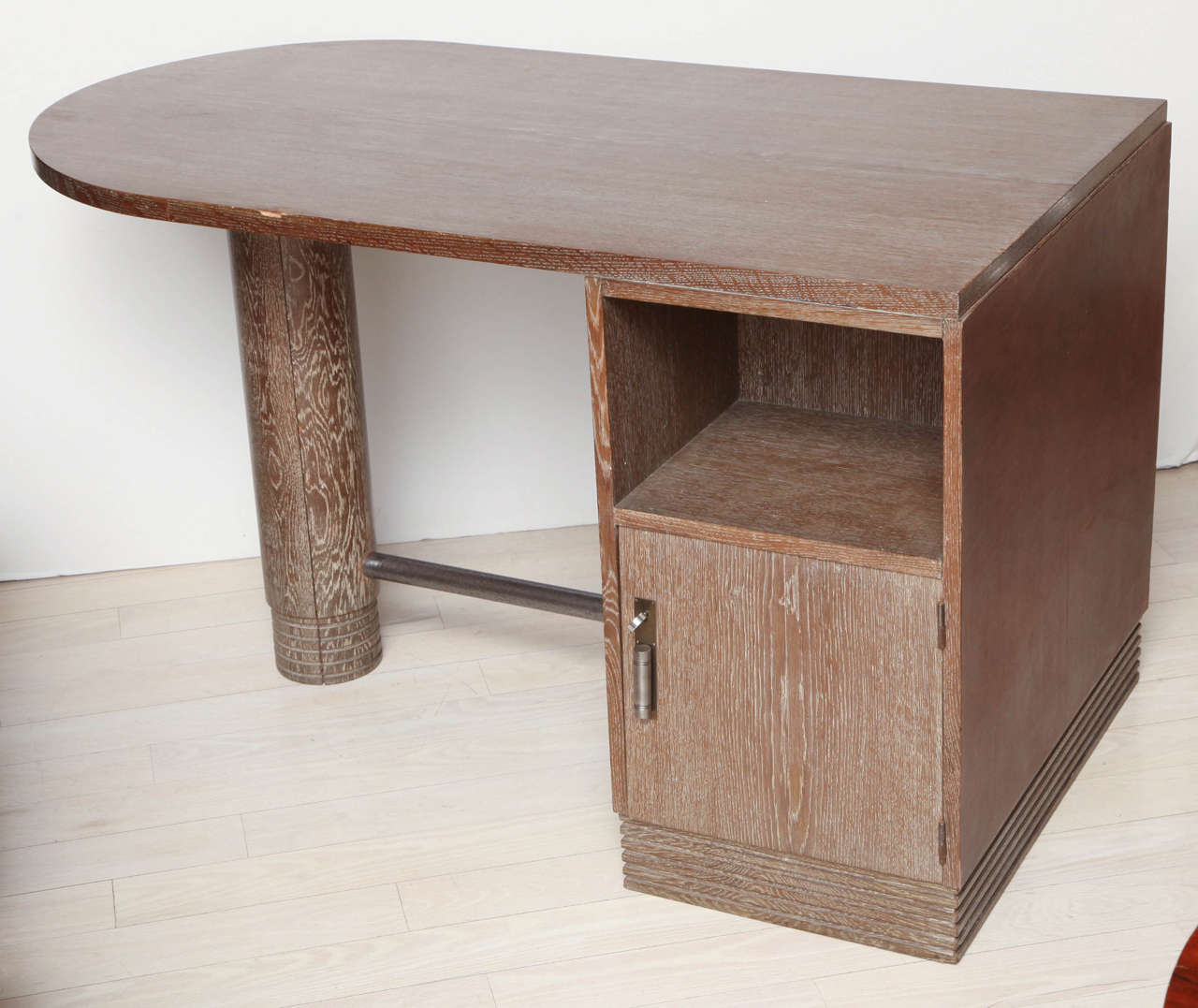 Cerused oak desk, the shaped top raised on one pedestal and one column, the pedestal fitted with doors and shelves.