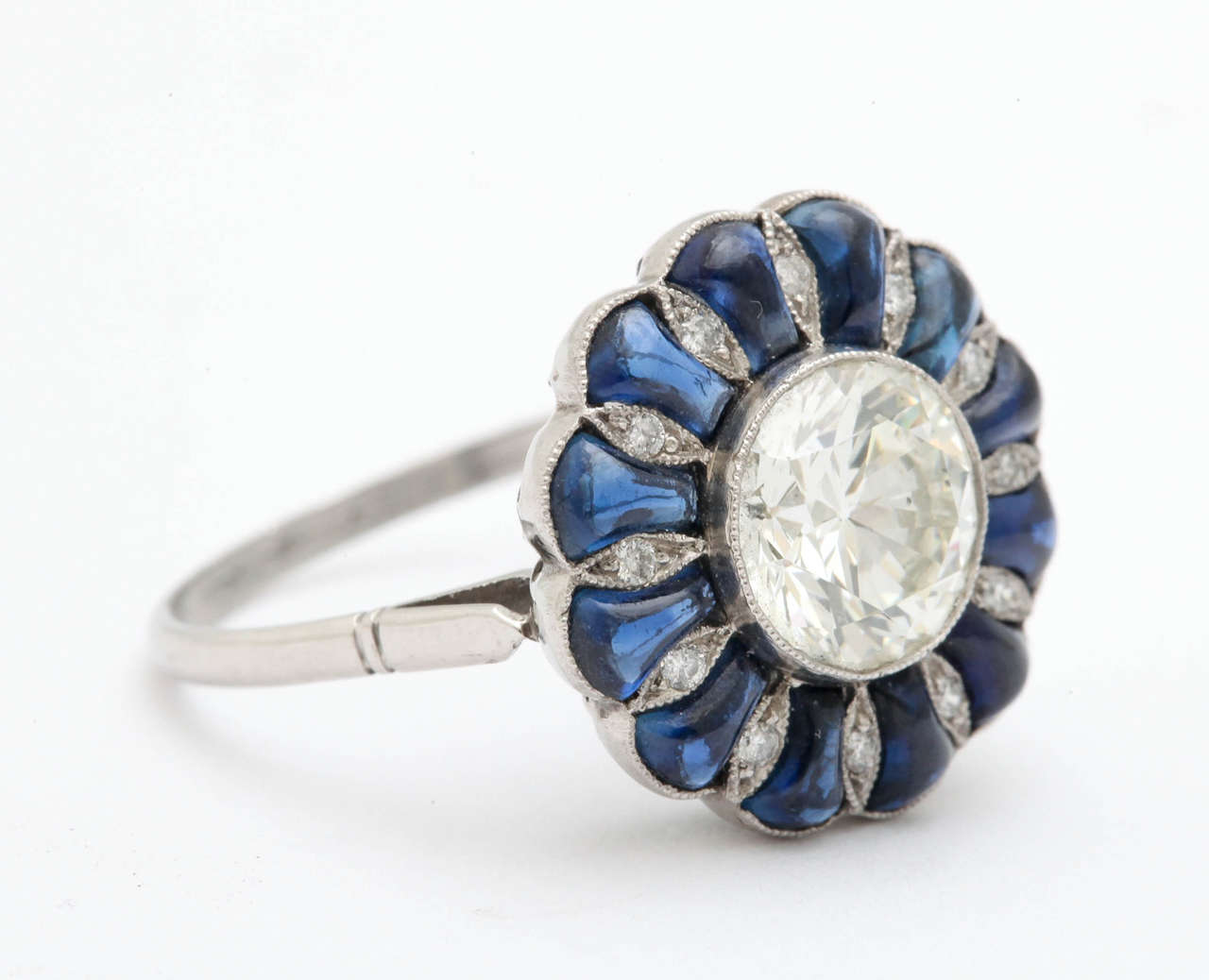 A beautiful mine cut 1.20 carat diamond surrounded by cabochon sapphires and smaller stones in a platinum setting.