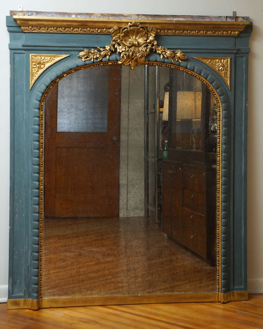 Here is a beautiful Neoclassical style mantel mirror with carved fruit detail and a center shell motif. The circa date for this mirror is the late half of the 1870's to 1890's.
The frame was painted in the 20th Century in a pale turquoise and a