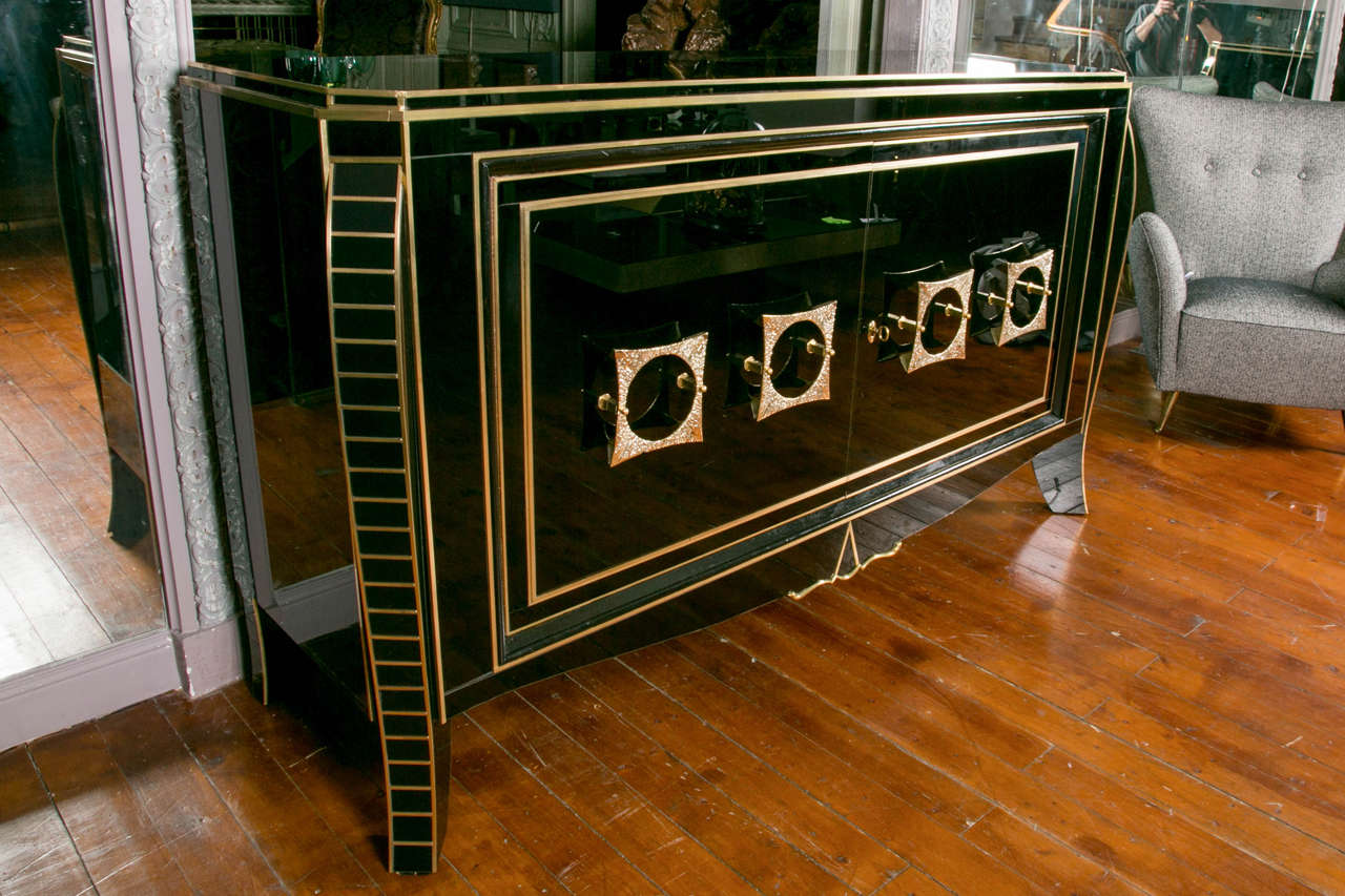 Pair of sideboards in black mirror and brass fillets, two doors decorated with brass sculptures, four feet, shelves inside.