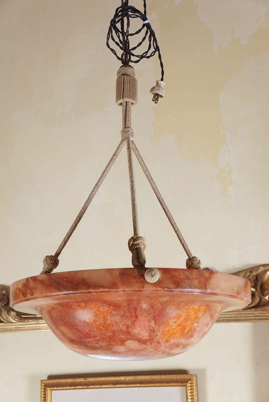 This lovely and richly colored bowl fixture was made in France during the Art Deco period circa 1920. Crafted from a brownish ,orange colored alabaster and designed to give a soft golden light down into a room with bright light shinning on the