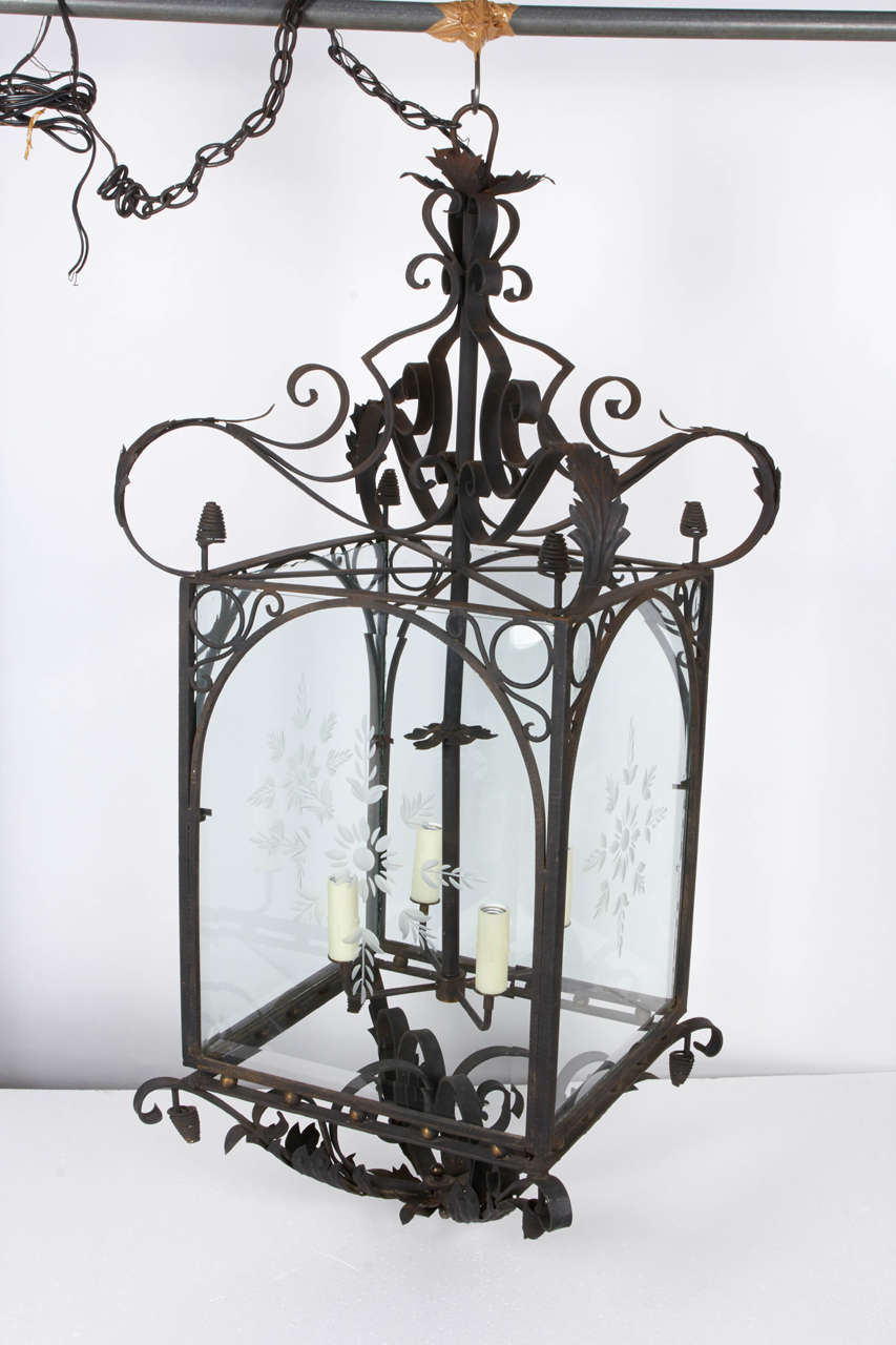 Elegant scrolls of wrought iron extend from the cube-like structure of this antique light fixture. Four etched glass panels add a lovely character and complement the iron acanthus design along the structure. Fixture is supported by an iron chain and
