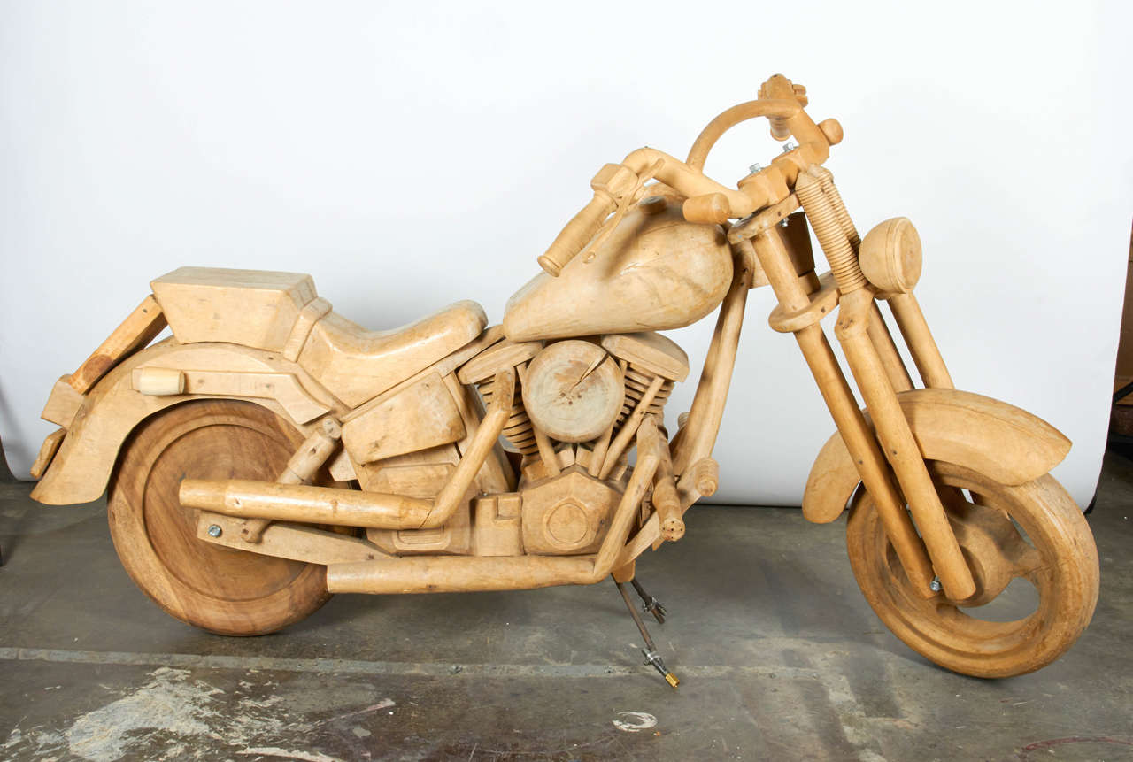 A rare find, this replica of a motorcycle is made entirely of wood, with the exception of the kick stand and the nuts/bolts which hold the piece together. This sculpture rolls when pulled and remains stationary with the kick stand down. The wood is