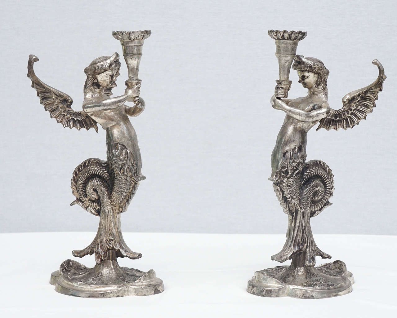 Pair of Continental silvered-metal winged mermaid candlesticks.