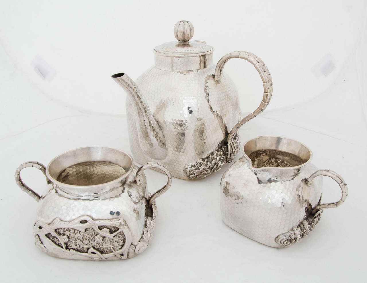 A fine antique silver Chinese silver 3 piece teaset with floral and tree bark decoration on a hammered background.
The teaset was made by Tu Mao Xing, Jiujiang, circa 1895.
Total weight is 1291 gms.