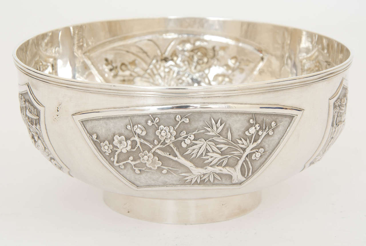 Chinese export silver bowl, the sides embossed with four panels showing figural scenes, bamboo, chrysanthemum and prunus.