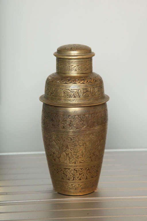 A cocktail shaker of typical form entirely engraved with bands of leaves and flowers. Lined in silver.