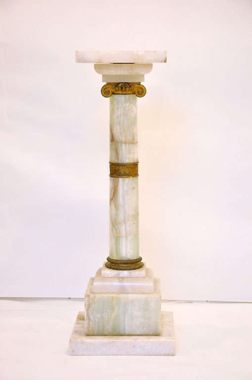 French Empire onyx pedestal, warmly veined onyx pedestal with square pivoting top surface surmounting regal shaft in the form of  classical style fluted Ionic column shaft, gilded bronze scrolled volute capital, gilt bronze detailed waist with