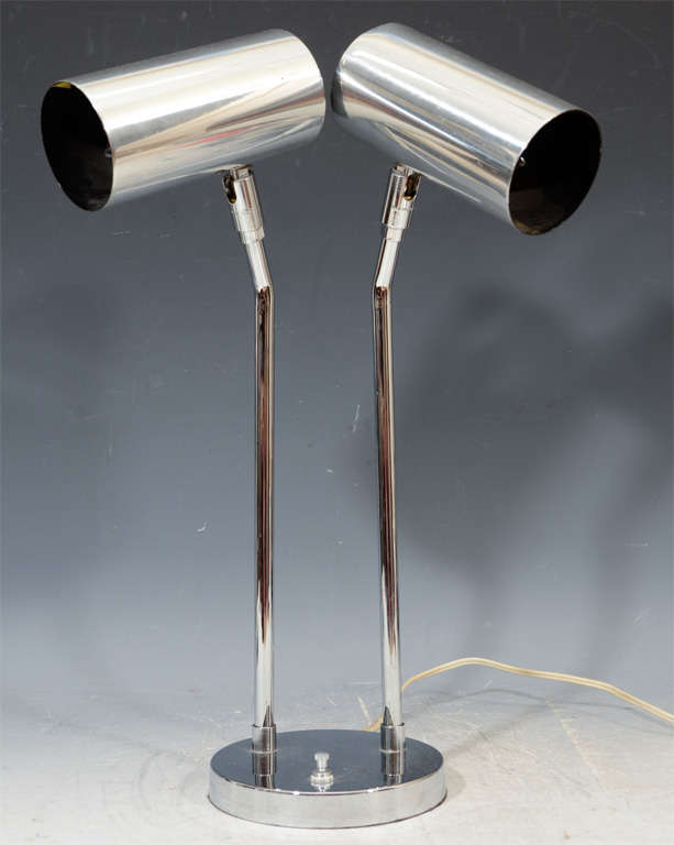 A vintage desk lamp by Koch and Lowy with two cylinder lights and a round base. Each light is articulated; pivoting up and down and swiveling side to side.