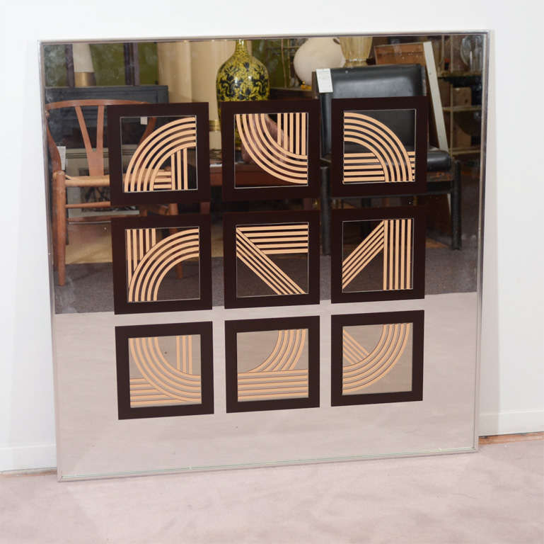 A vintage mirror with squared off areas decorated with abstract geometric lines. When viewd as a whole, the lines from square to square seem to flow into one another.