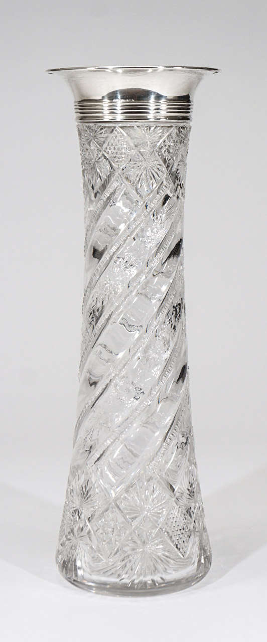 Ce vase en cristal très haut et de forme élégante présente une combinaison de taille géométrique de la période American Brilliant alternant avec une décoration florale gravée à la roue de cuivre sur un corps taillé en spirale. Le corps soufflé à la