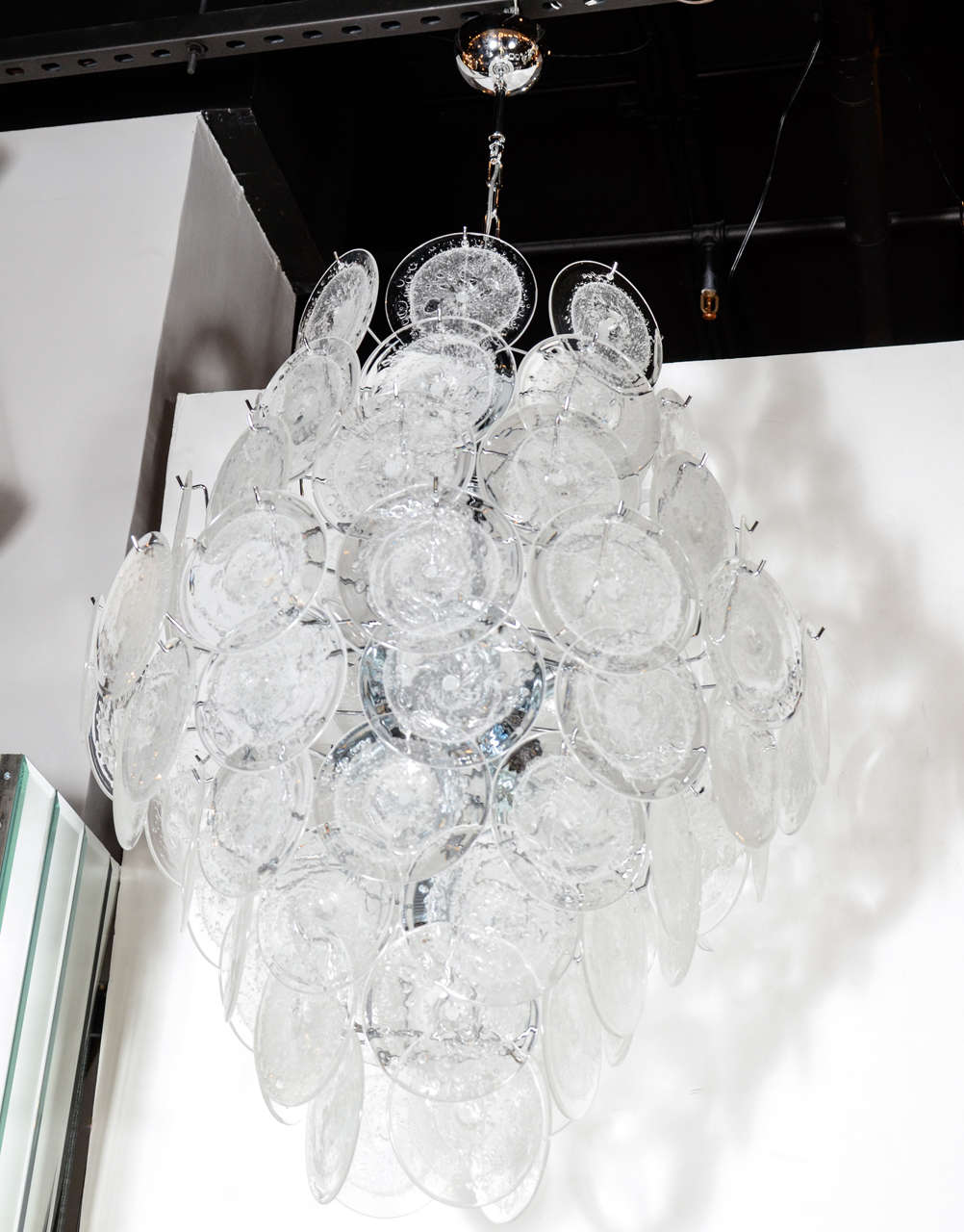 This exceptional chandelier by Vistosi boasts 84 Murano Glass Discs suspended in a diamond formation. Each disc is made by hand and incorporates a central opaque texture suspended in the glass.