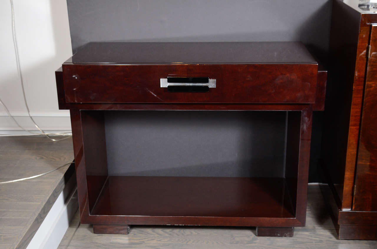 This spectacular Art Deco Machine Age console/writing desk by Donald Deskey in book matched mahogany features a stepped open base, large sectioned drawer perfect for storage and a black lacquer and brushed aluminum pull. This would either be a great