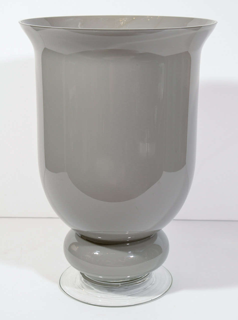 Gorgeous pair of hand blown Murano glass urn vases. The urns have a medium smoked grey cast and have bulbous lower details with clear Murano glass footed bases. Great option as a pair of centerpieces.