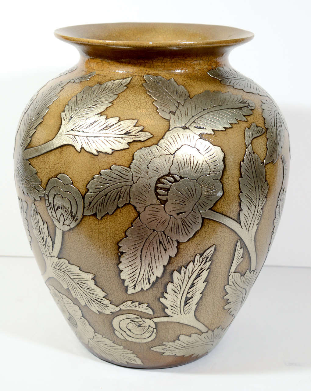 Large ceramic pottery vase with classic urn form. The vase has bronzed or sepia colored exterior with crackle finish and with floral relief overlays in silver leaf. Includes porcelain lid with stylized floral designs in a white glaze finish (as seen