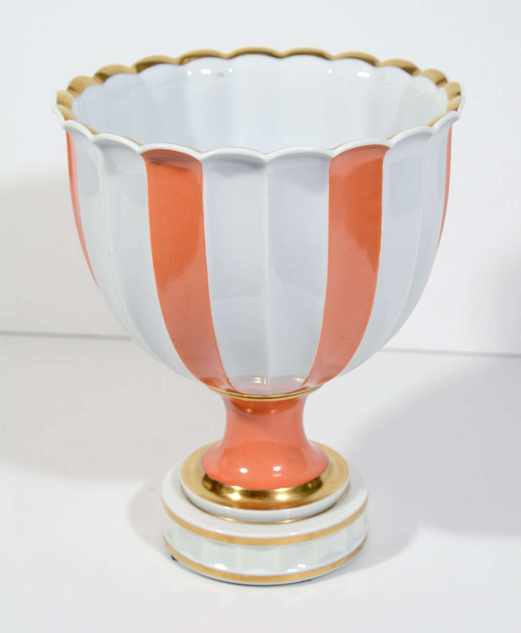 Gorgeous porcelain footed bowl with classic urn form.  Urn has a fine glaze finish in white with persimmon stripes and with hand finished gold leaf details. Also features scalloped brim and fluted design with detaiil with plinth base design. Signed