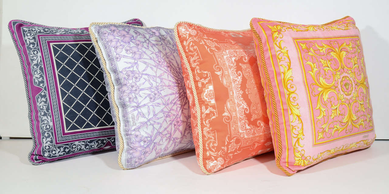 Four vintage Versace decorative pillows with distinguished and renowned scarf prints. The pillows are in silk or velvet and feature a variety of vibrant colors and patterns.  They have braided welting and all carry the Versace logo/signature.  Can