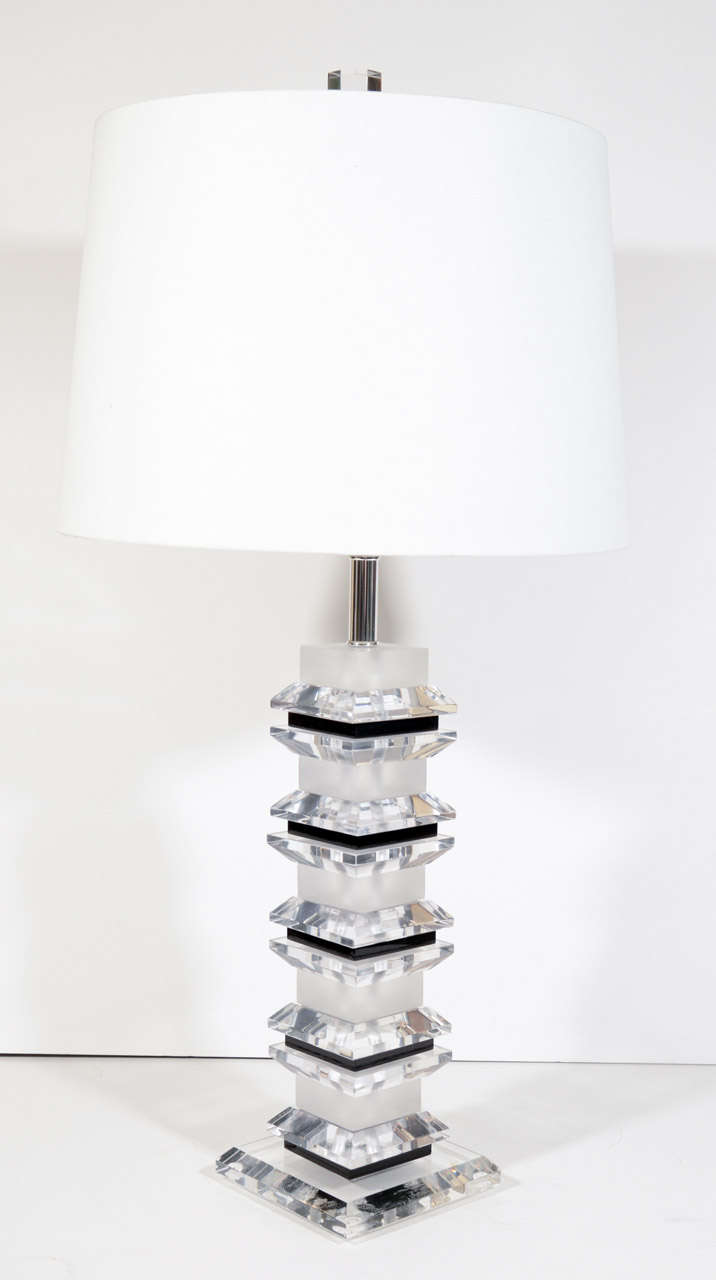 Pair of modern lucite table lamps comprised of stacked clear, frosted, and black lucite blocks and beveled squares. Lamps have an Art Deco (Machine Age) inspired design and have chrome stems and fiitings. Shown with custom drum shades in white