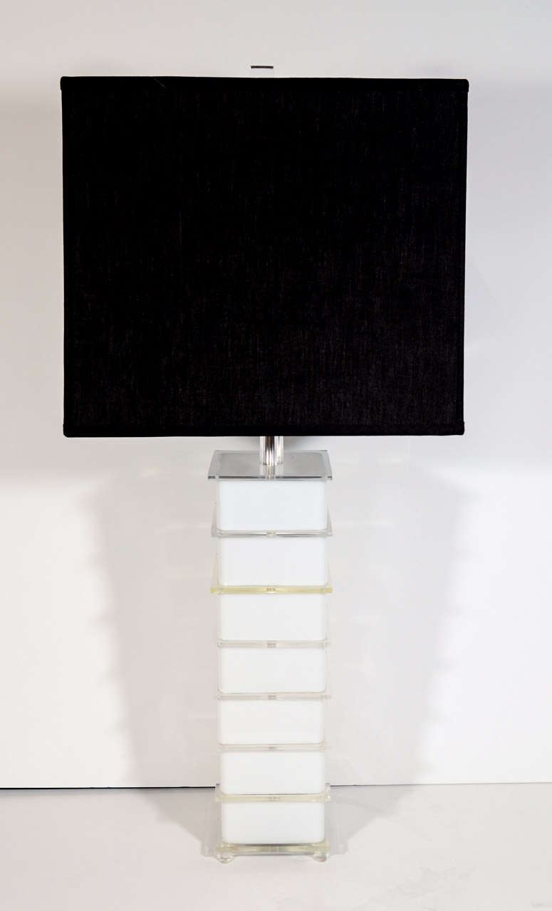 Pair of mid century modernist lucite lamps.  The lamps are comprised of alternating stacked clear lucite panels and white opaque lucite cubes.  The lamps have fluted lucite over chrome stems and lucite finials.  Shown with custom black linen cube