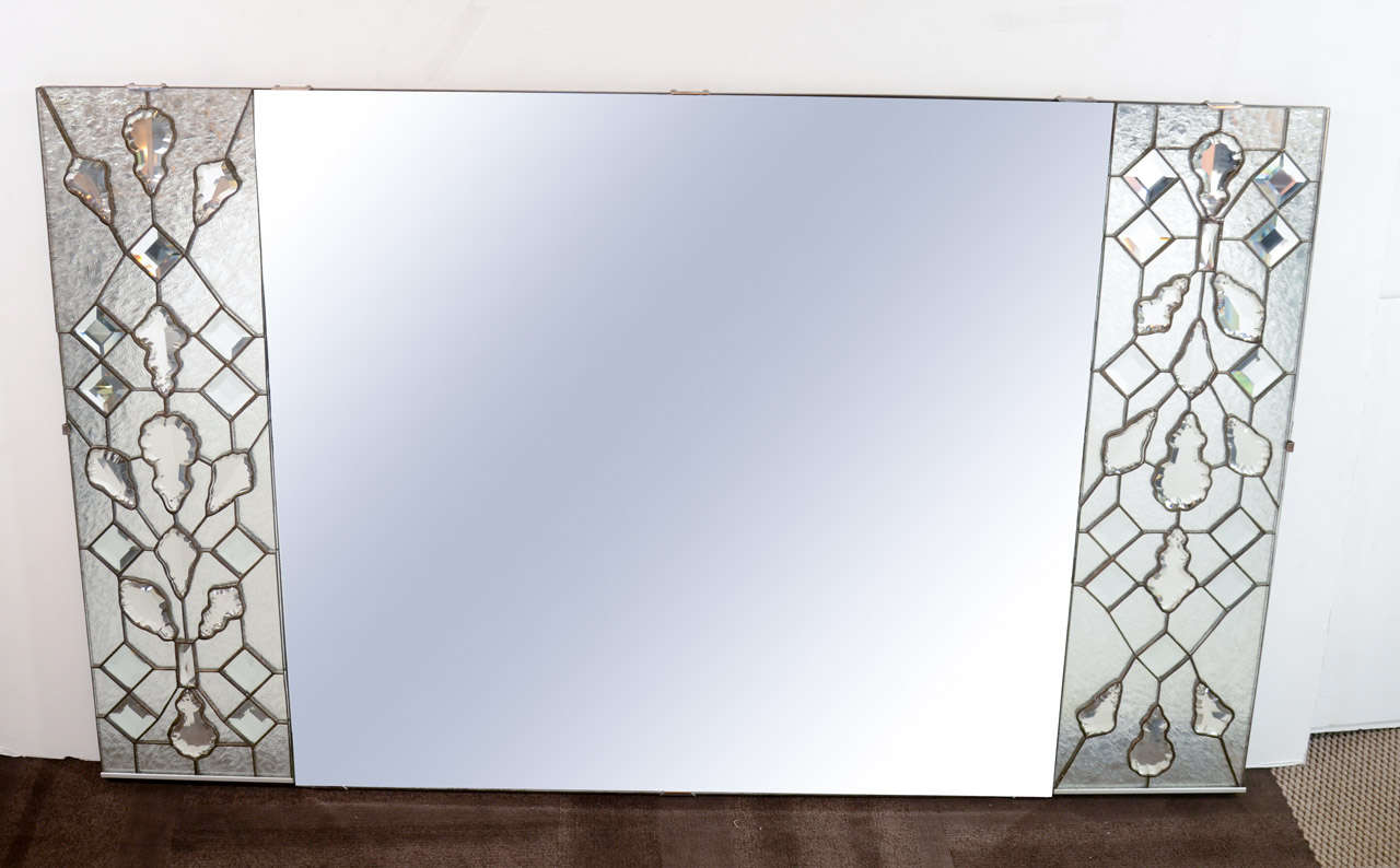 Spectacular rare Hollywood rectangular mirror comprised of large center with hand beveled border design, and with stylized side panels. The sides are comprised of textured glass panels over mirrors, much like stained glass windows. The panels have