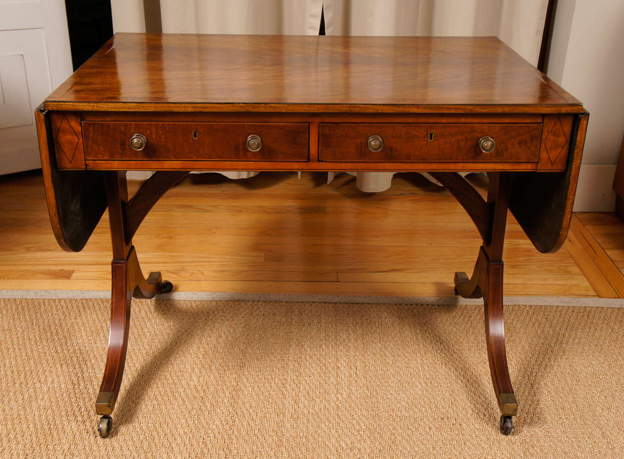  George III style drop leaf sofa table on casters with four drawers and original brass pulls. Mahogany with cross banding.
Dimensions:
37.5
