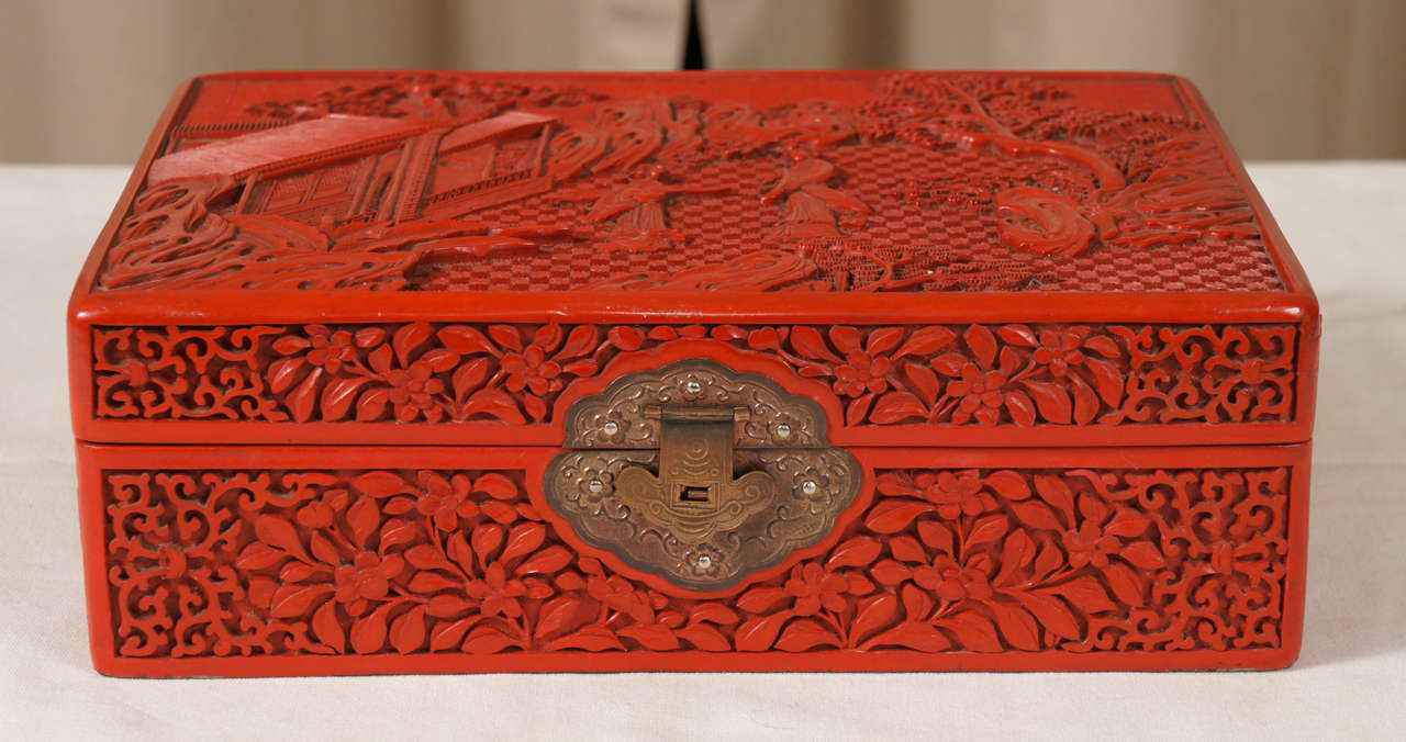 Fine cinnabar lacquer box with deeply carved scrolls, foliage and garden court scene on lid and gilt claps. 