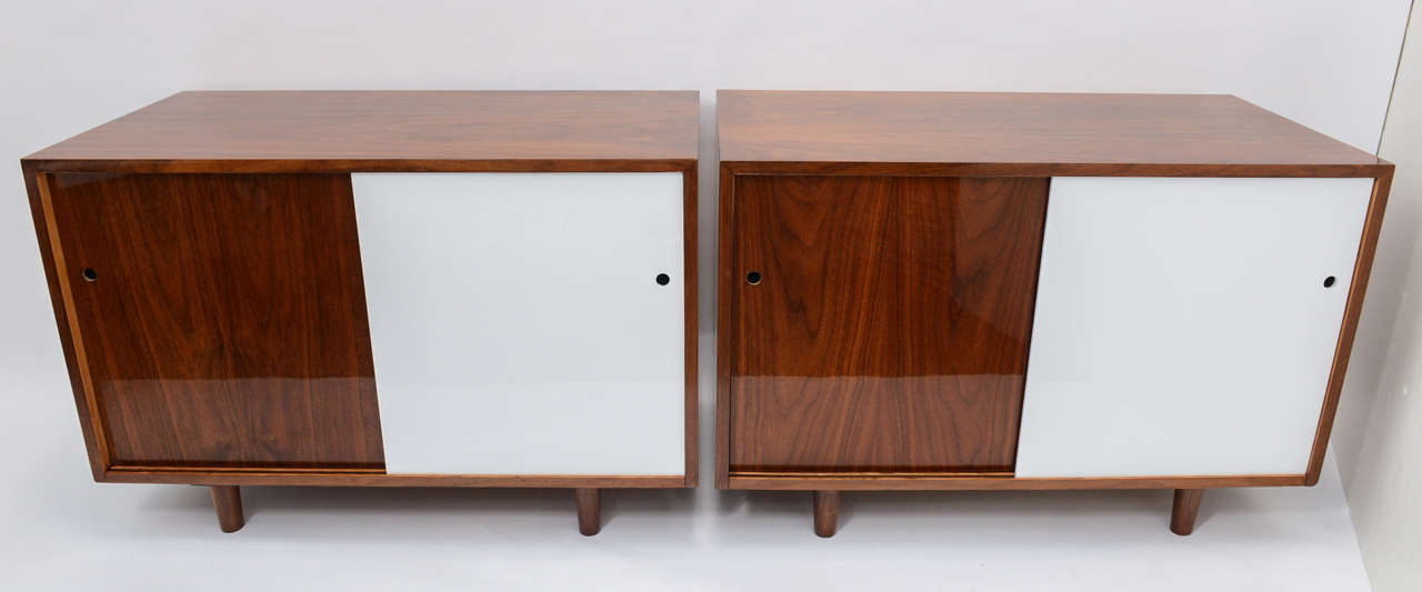 These two beautiful credenzas have been expertly refinished and updated.  All the natural teak markings shine under a fresh coat of high gloss lacquer, while one of the sliding doors has whimsically been lacquered in white. The fresh white door on