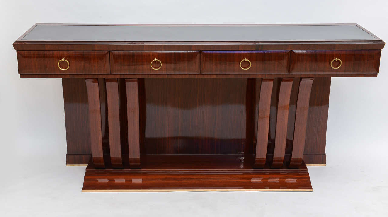The rectangular top with inset black glass above four drawers with brass ring pulls above scrolling supports.