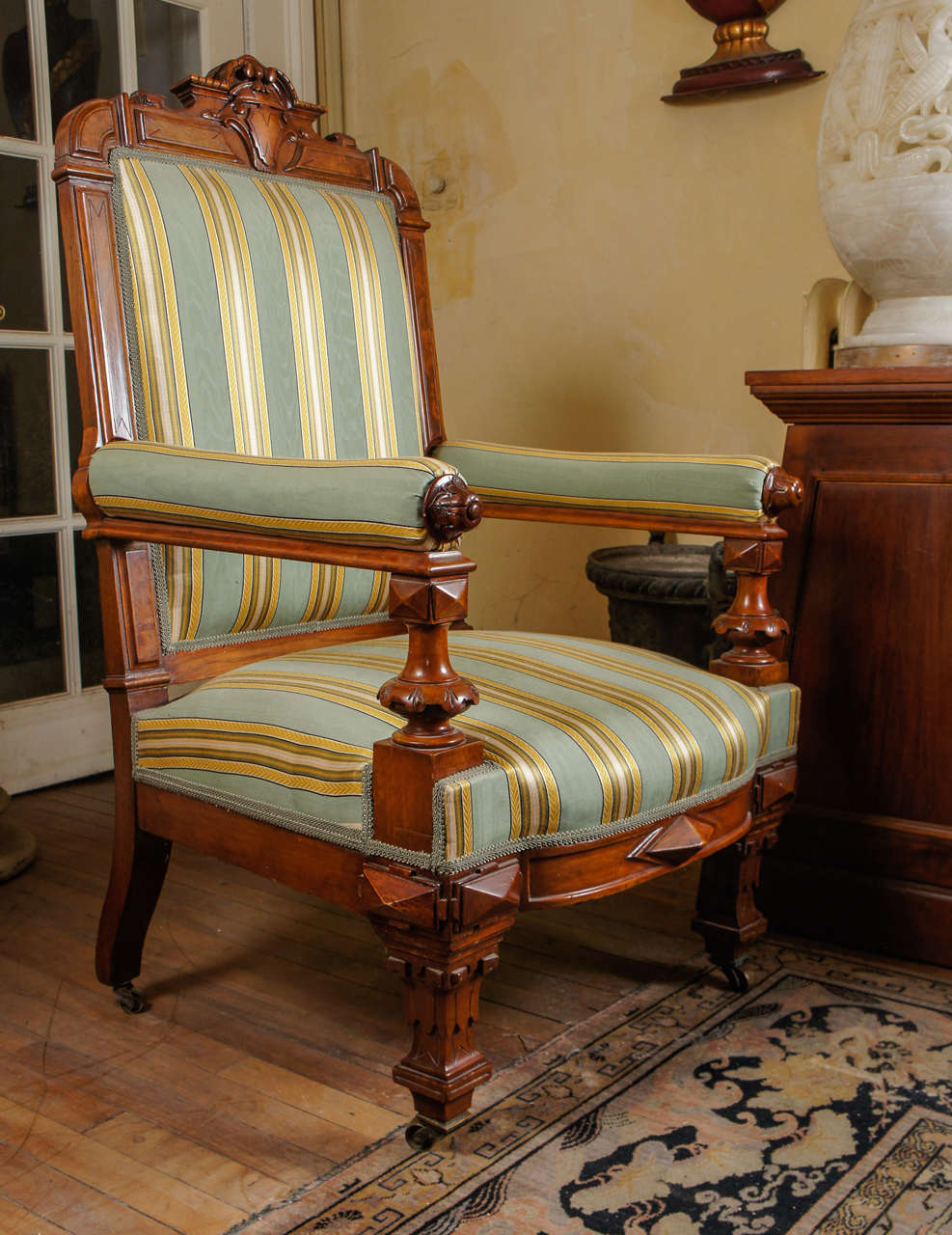 This large-scale and masculine chair made in America circa 1860 was crafted in walnut and fine walnut figured veneers. The large flat plains are accentuated with figured veneers set within ebonized incised lines. The leg supports and lower apron are