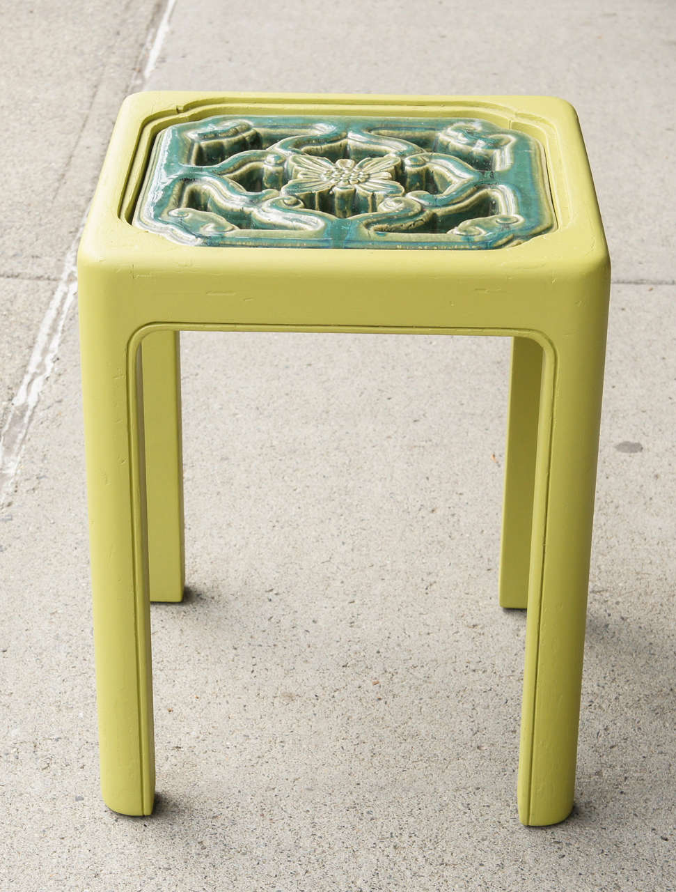 This fun small low table made circa 1960 is formed from an old Chinese architectural tile placed within the shaped top of the table. Left open at the back so that the double sided tile reads thru with negative space the wood table is painted in a