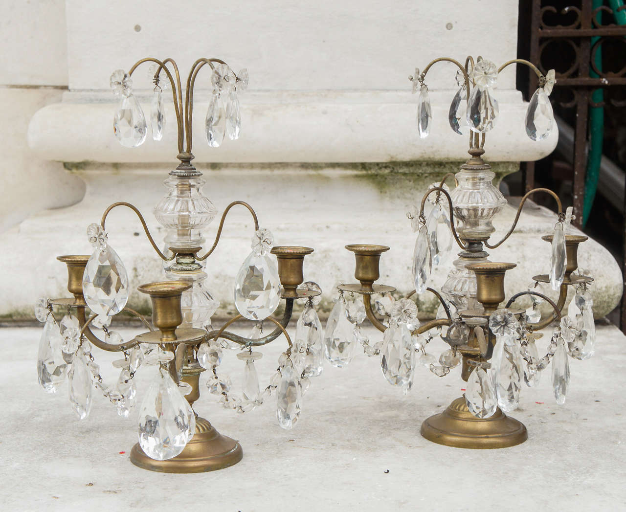 This lovely pair of 3 light lusters or candelabra are made in the Louis XVI style in France in the early 2oth century. This simple cast brass body or frame is decorated with blaster shaped spacers creating the upright section terminating in a brass