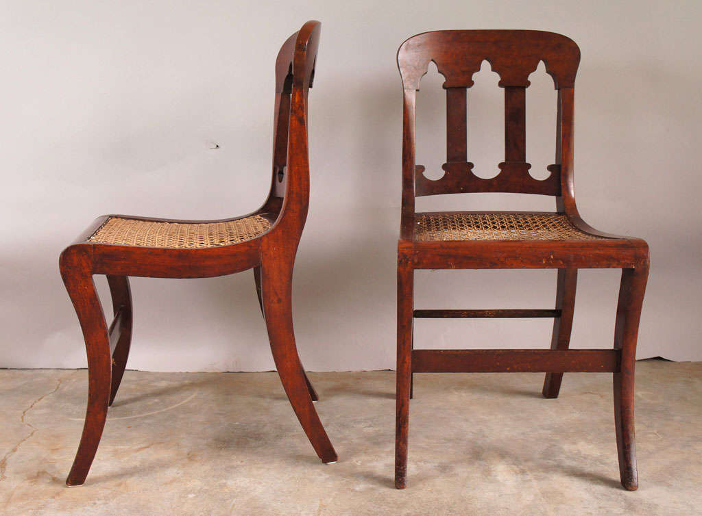A matched pair of mahogany side chairs with gently scrolling gothic archways in back splat, and sabre legs. A pleasing form with delicate curves from every angle.