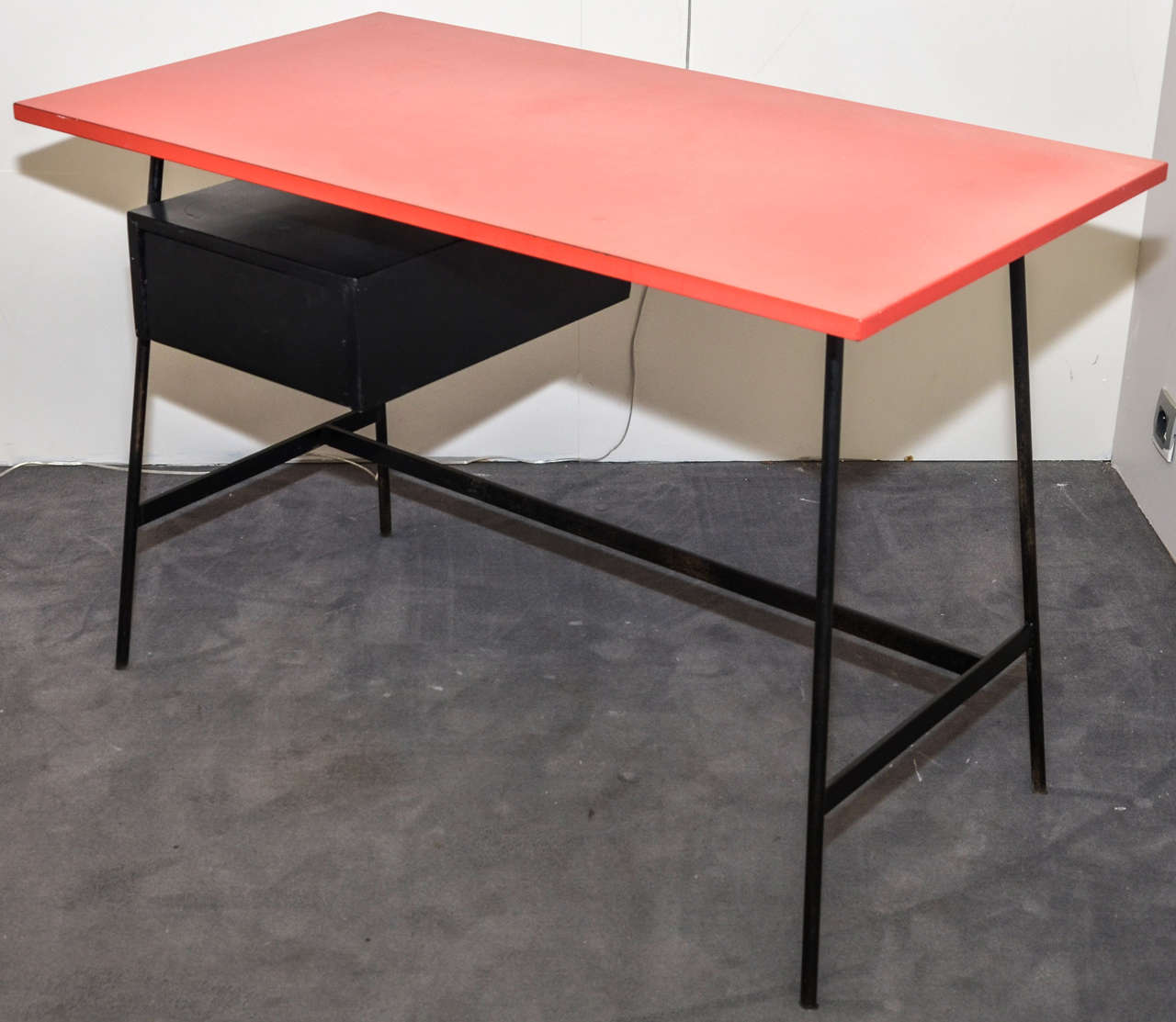 1950s desk by Pierre Paulin with base in black patina metal; top surface in red melamine; one wooden drawer in black patina.