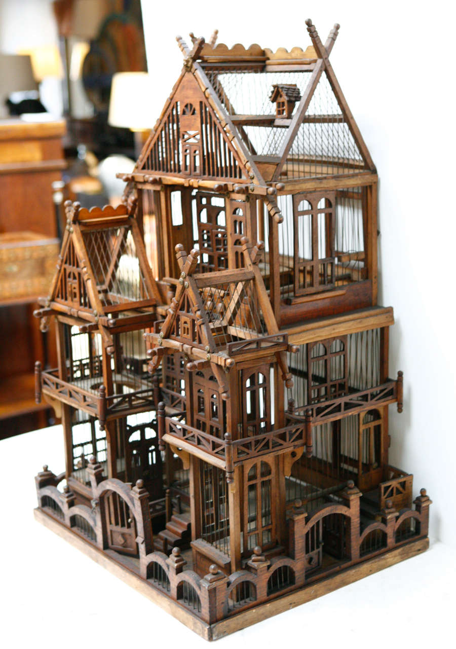 An elaborate architectural wooden and metal cage with bird perches and doors