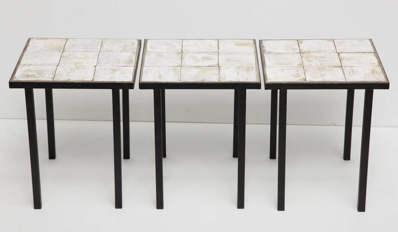 A set of three tables in wrought iron with white ceramic tile tops