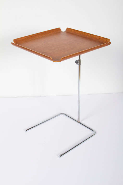 A re-issue adjustable height tray table in molded walnut plywood and chromed steel frame. Model no. 4950. By George Nelson for Herman Miller. American, circa 1980.