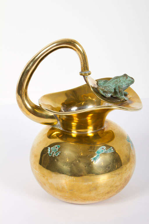 A brass pitcher in a round form with a patinated bronze frog figure resting on its spout and inlaid ceramic malachite figures around the top of the body. Maker's mark stamped to the base. By Los Castillo, Taxco. Mexico, circa 1950.