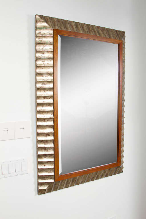An elegant beveled mirror with a thin cherry inner frame held within a wide fluted and beveled frame in a glamorous silver leaf finish. With manufacturer's label to the back. Designed by John Black for Baker Furniture. U.S.A., circa 1997.