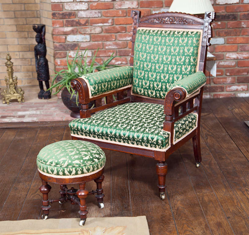 OAK WOOD ART CHAIR WITH FLARED  ARMS AND HAND CARVINGS ON BACK- WOVEN GREEN AND BUFF FABRIC WITH GIMP TRIM- UNIQUE ITEMS- CASTORS 
ON BOTH CHAIR AND STOOL-STOOL 13