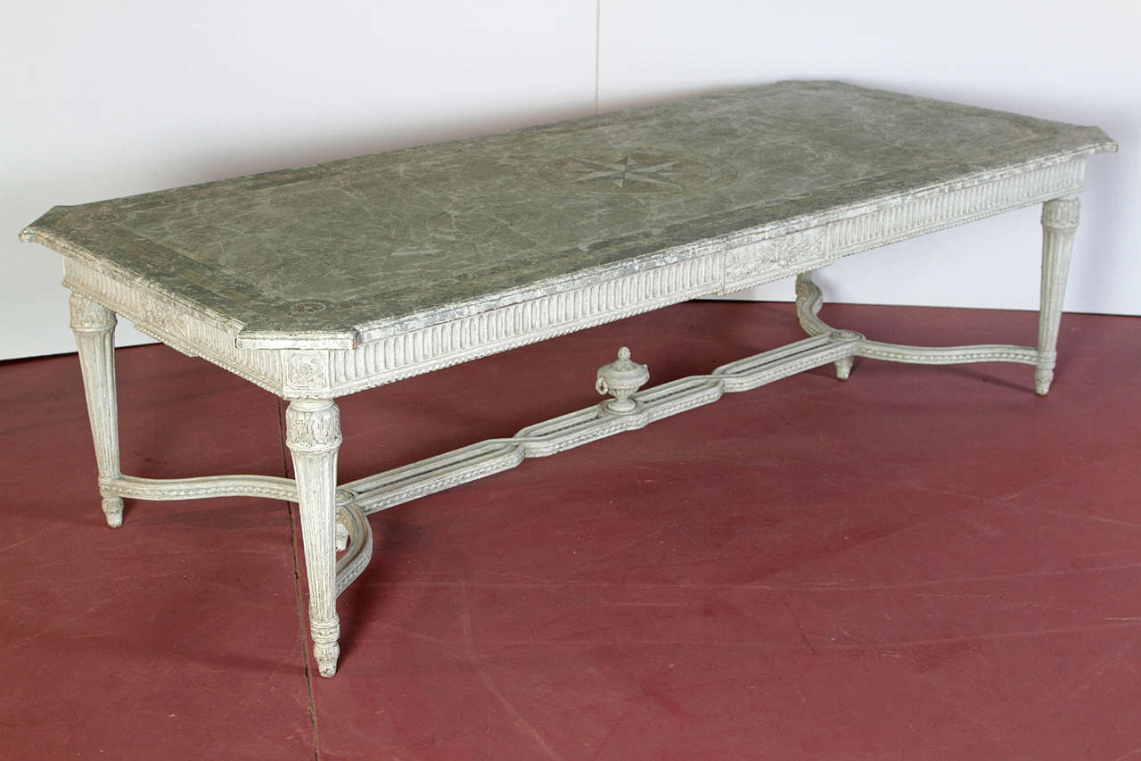This exceptional, antique Louis XVI painted dining room table was crafted in northern France, circa 1860. The table has a faux marble top, a carved apron, tapered legs, and an intricate stretcher with a carved finial in the middle. The top is