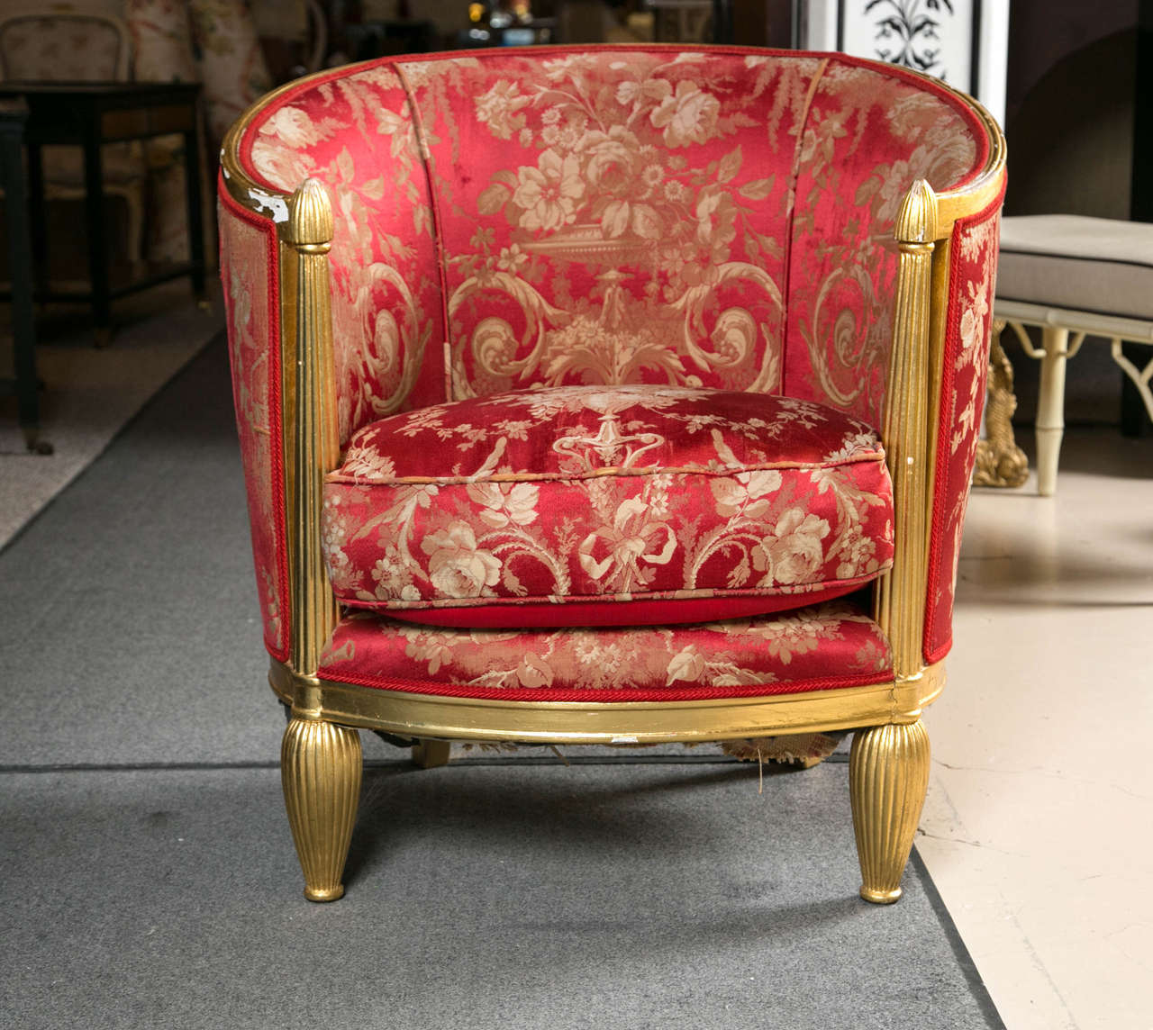 Art Deco giltwood chair. The distressed gilt wooden frame in the art deco fashion. Fabulously covered in a (cat on a) hot tin roof red fabric representative of the exotic accent colors that are an iconic color trait of the era. With a splash of gilt