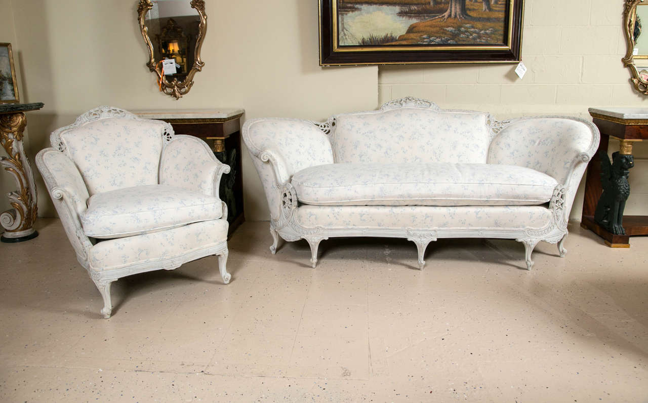 Louis XV style sofa with matching wing chair Swedish paint decorated. The down cushions add to the soft and subtle design of the fabric. White background displaying small bouquets of soft blue roses wrapped in baby's breath add to the beauty of this