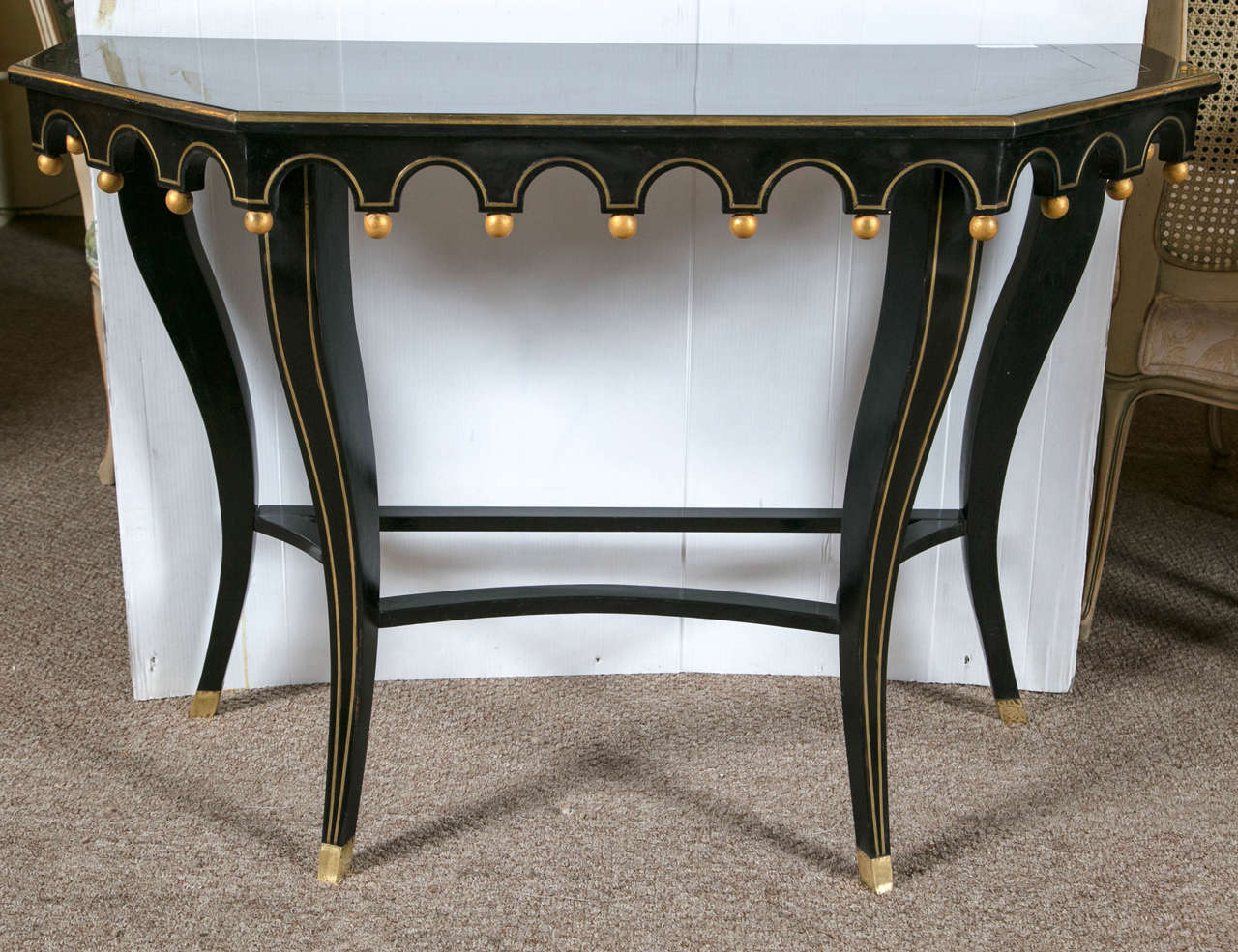 Pair of ebonized and gilt decorated console tables in the by Maison Jansen. Wonderfully and uniquely decorated with a ball at the end of a drop point on the apron reminisce of The Court Jester or Jestress's tassels, beads or bells. A unique