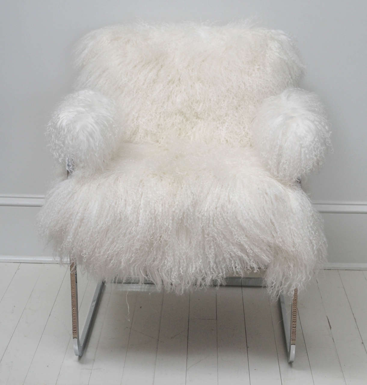 Very chic and elegant. Pair of Mid-Century Modern cantilever armchairs in polished chrome frame and newly upholstered in a natural silky white long haired Argentine Mongolian goat hide. Very comfortable and sturdy, these chairs make quite a dramatic