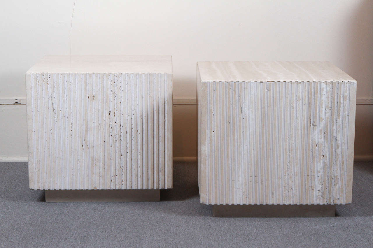 Pair of polished travertine cubes. The sides are carved with vertical grooves and they sit up on small travertine bases. Perfect as a pair of stylish end tables, or side by side as a pair of small coffee table.
